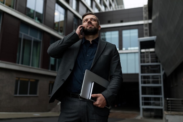 Odnoszący sukcesy europejski dziennikarz rozmawia przez telefon na tle centrum biznesowego
