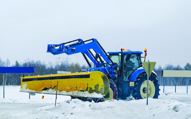 Odśnieżanie Traktor w zimowej drodze w Finlandii. Samochód dostawczy w pracy na podjeździe. Transport europejski. Transport wiejski na zaśnieżonej autostradzie.