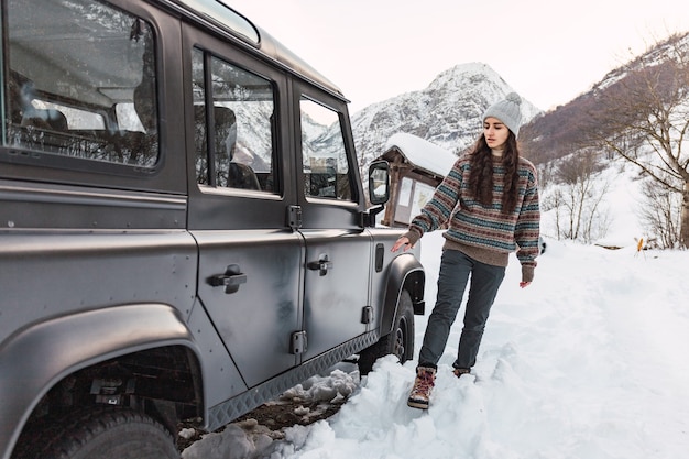 Zdjęcie odważna młoda dziewczyna wsiada do samochodu na górze w zaśnieżonych alpach w północnych włoszech.