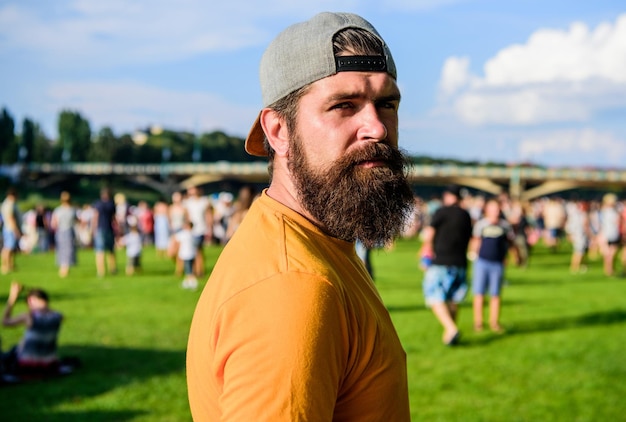 Odwiedź letni festiwal Hipster w czapce szczęśliwie świętuj wydarzenie fest lub festiwal Letni fest Mężczyzna brodaty hipster przed tłumem Koncert na świeżym powietrzu Strefa kibica Festiwal muzyczny Koncepcja rozrywki