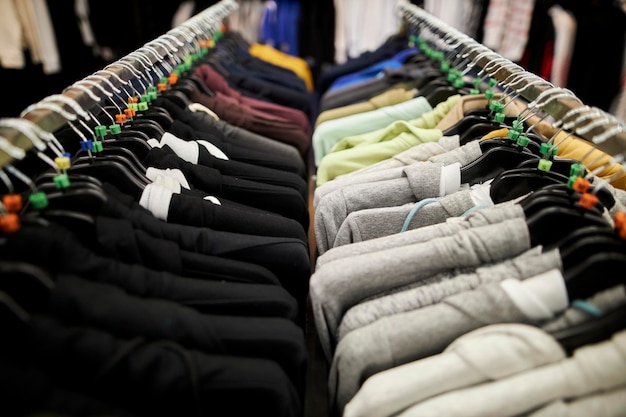 odzież męska - kolorowe koszulki, bluzy z kapturem i bluzy na wieszaku w sklepie odzieżowym