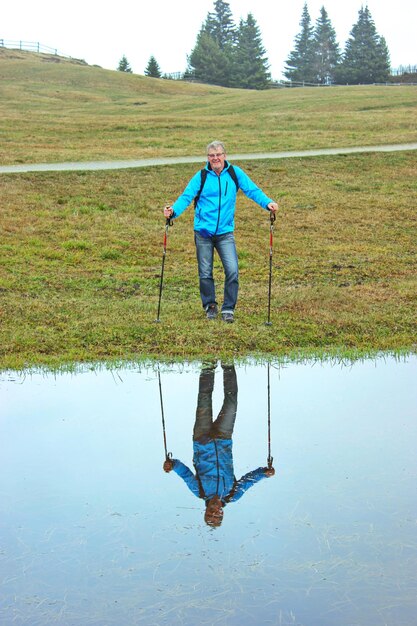 Zdjęcie odzwierciedlenie człowieka z pałkami wędrownymi stojącego w jeziorze