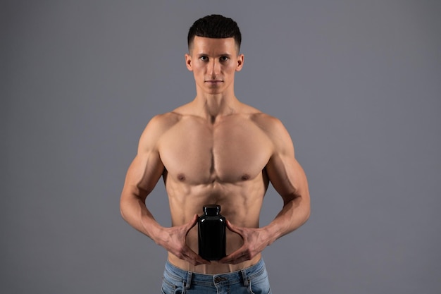 Odżywka dla sportowców Mężczyzna bez koszuli trzyma suplementy diety Suplementy diety