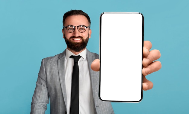 Oferta mobilna przystojny biznesmen trzymający telefon komórkowy z pustym ekranem pokazującym urządzenie z makietą