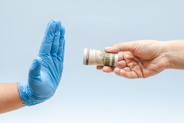 Ofiarowanie pieniędzy w ręce pielęgniarki lub lekarza w niebieskiej rękawiczce chirurgicznej Korupcja