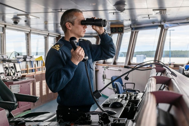 Oficer pokładowy z lornetką na mostku nawigacyjnym Marynarz na pokładzie statku Żegluga handlowa