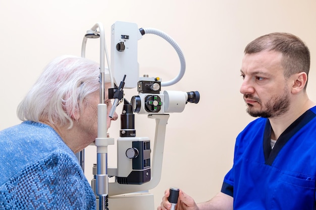 Oftalmolog mężczyzny sprawdza wzrok dorosłej kobiety za pomocą nowoczesnego urządzenia z