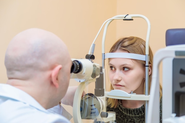 Oftalmolog sprawdza wzrok młodej dziewczyny za pomocą nowoczesnego urządzenia z wiązką światła