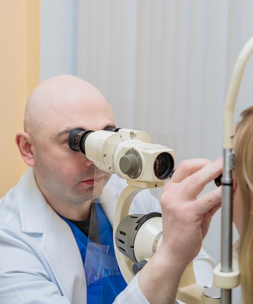 Oftalmolog sprawdza wzrok młodej dziewczyny za pomocą nowoczesnego urządzenia z wiązką światła