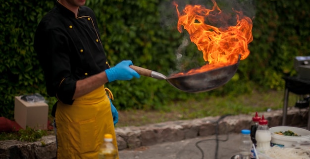 ogień na patelni Profesjonalny szef kuchni w komercyjnej kuchni gotowanie w stylu flambe Chef Flambe Cooking