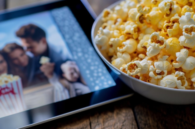 Zdjęcie oglądanie komedii na tabletie z miską z popcornem