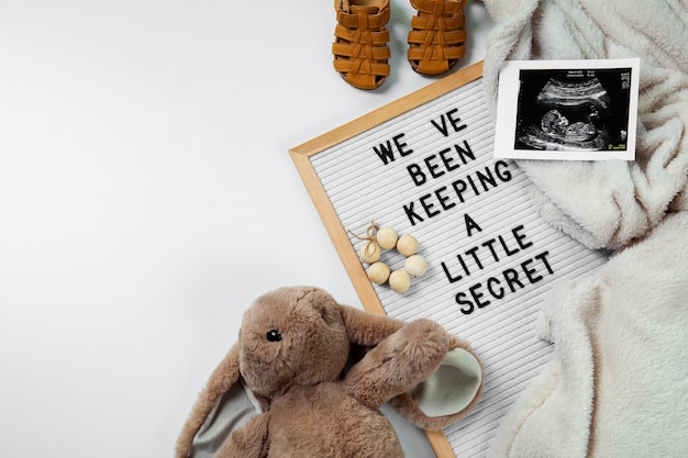 Zdjęcie ogłoszenie o ciąży w widoku z góry z artykułami dla niemowląt