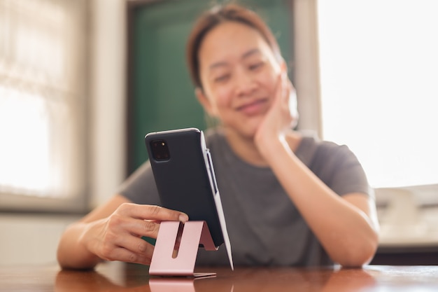Ogólnospołeczna dystansująca szczęśliwa uśmiechnięta kobieta używa telefonu komórkowego wideo rozmowy rodzinnego.