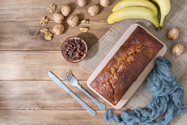 Ogólny widok chleba bananowego z orzechami, rodzynkami i bananami na rustykalnym drewnianym tle