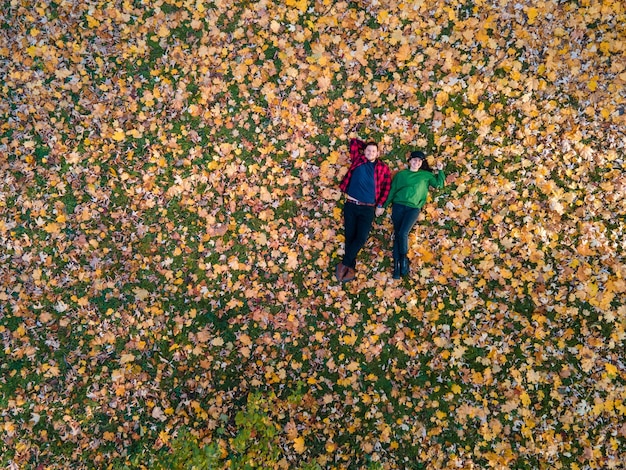 Ogólny widok kobiety z mężczyzną leżącej na ziemi pokrytej jesiennymi liśćmi