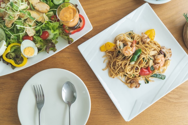 Ogólny widok stołu przygotowanego przez sałatkę i spaghetti do jedzenia.