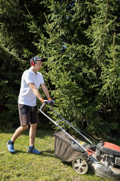 Ogrodnik koszący trawę kosiarką spalinową