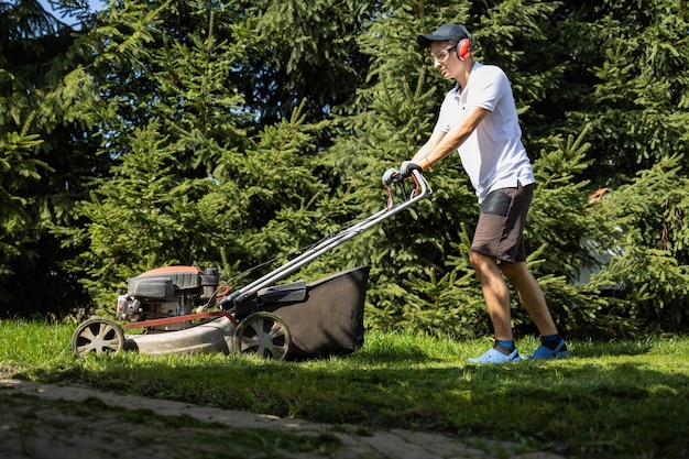 Ogrodnik koszący trawę kosiarką spalinową