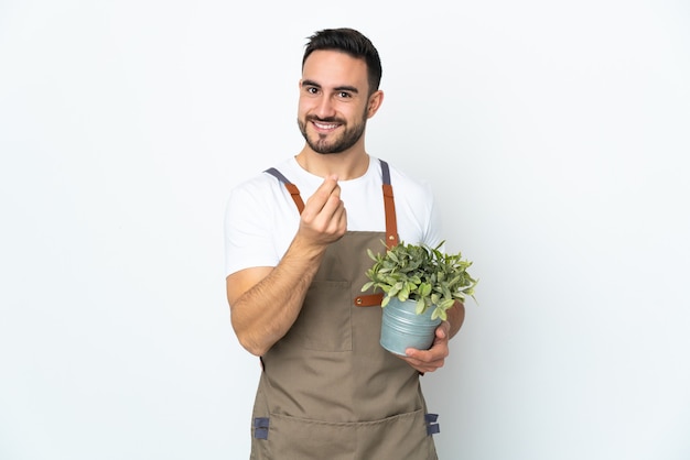 Ogrodnik mężczyzna trzyma roślinę na białym tle na białym tle zarabianie pieniędzy gest