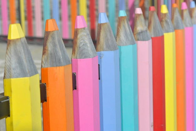 Ogrodzenie szkolnego boiska w kształcie drewnianych kolorowych ołówków