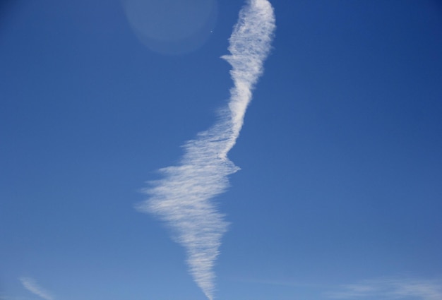 Ogromne smugi chemiczne lub smugi kondensacyjne na tle błękitnego nieba