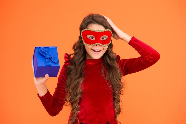 Oh la la Zaskoczone dziecko nosi maskę karnawałową Mała dziewczynka trzyma pudełko niespodzianek Otrzymanie świątecznej niespodzianki Niespodzianka urodzinowa Pakowanie prezentów Przygotowania do wakacji