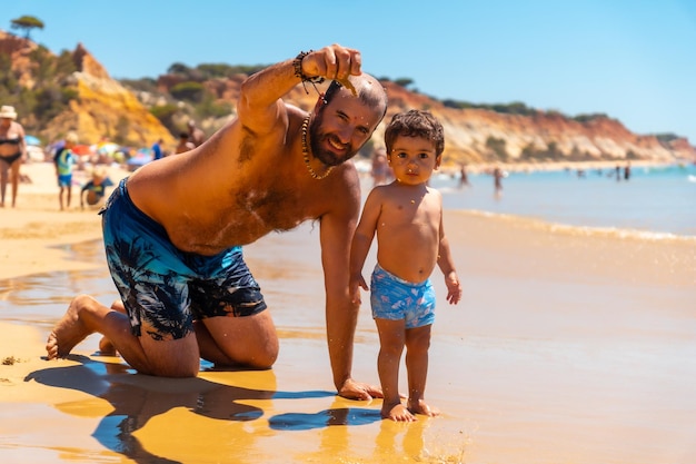 Ojciec bawi się w piasku z synem Praia do Barranco das Belharucas plaża Albufeira Algarve Portugalia