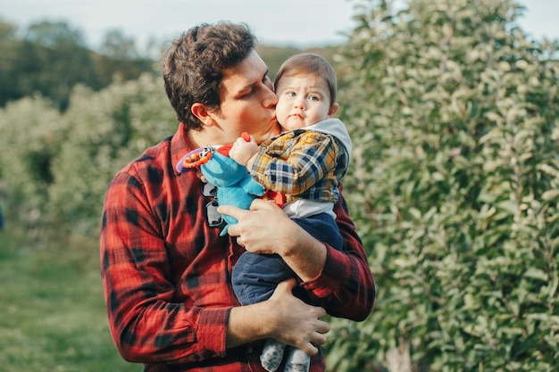 Zdjęcie ojciec całuje syna, stojąc w parku.
