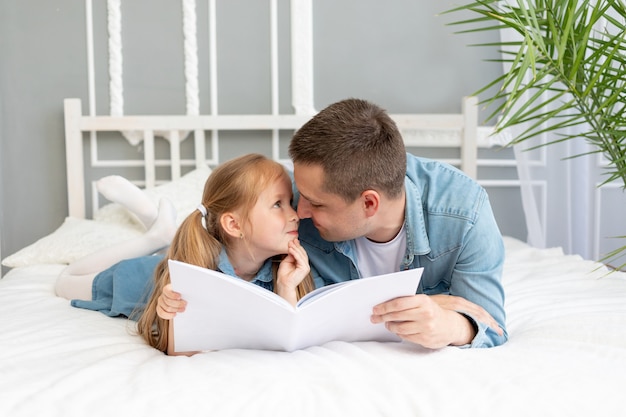 Ojciec czyta książkę lub studiuje z dzieckiem przed snem lub bawi się