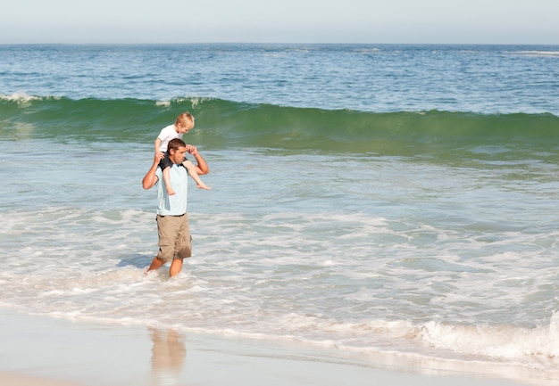 Ojciec daje synowi piggyback na plaży