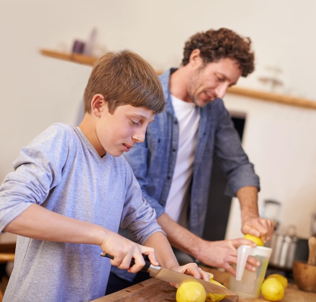 Zdjęcie ojciec, dziecko i cytrynowe owoce w kuchni do lemoniady, odżywianie na śniadanie, napoje do picia lub dobre samopoczucie, człowiek, syn i sprzęt do odciśnięcia soków w mieszkaniu lub świeże cytrusowe witaminy c lub zdrowie jelit