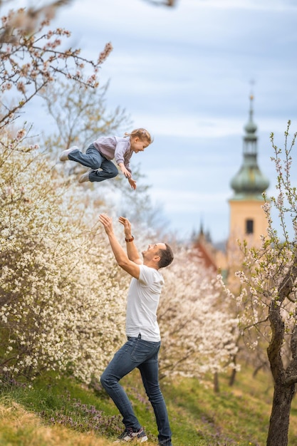 Ojciec i córka bawią się razem pod kwitnącym drzewem w wiosennym parku petrin w pradze euro