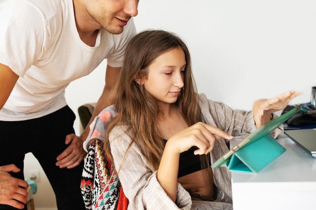 Zdjęcie ojciec i córka korzystają z tabletu cyfrowego siedząc w domu