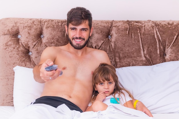 Ojciec I Córka W Sypialni Siedzą Na łóżku Oglądając Telewizję