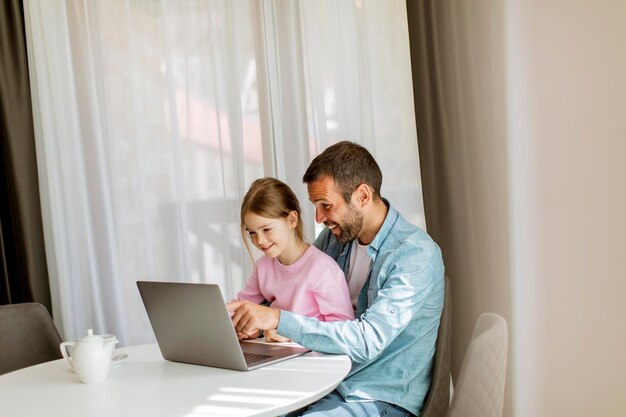 Ojciec i córka wspólnie korzystają z laptopa