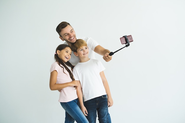Ojciec i dzieci robią sobie selfie na białym tle