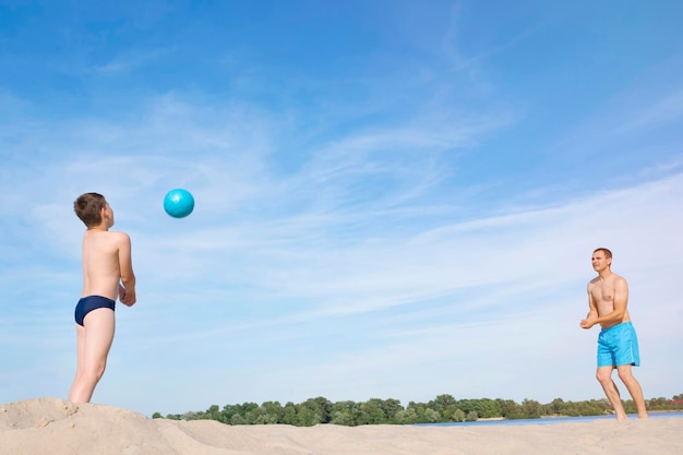 Ojciec i dziecko grają w siatkówkę plażową w słoneczny letni dzień