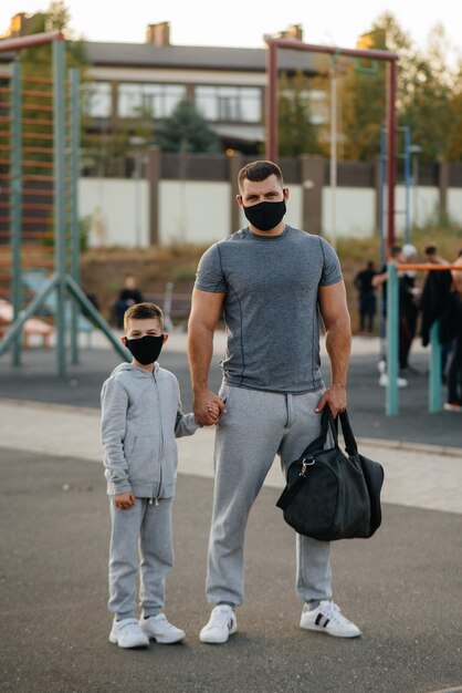 Zdjęcie ojciec i dziecko stoją w maskach na boisku po treningu podczas zachodu słońca.