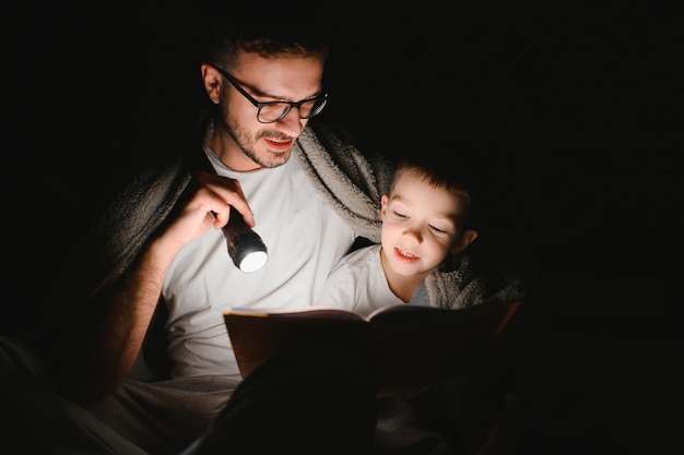 Ojciec i jego synek czytają bajki na dobranoc w domu