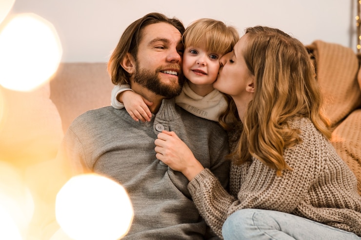 Zdjęcie ojciec i mama przytulają się i całują swoją ukochaną córkę siedząc na kanapie
