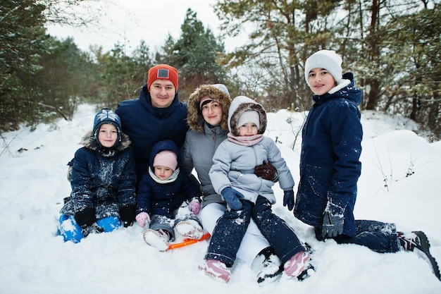 Ojciec i matka z czwórką dzieci w zimowej przyrodzie. Na zewnątrz w śniegu.