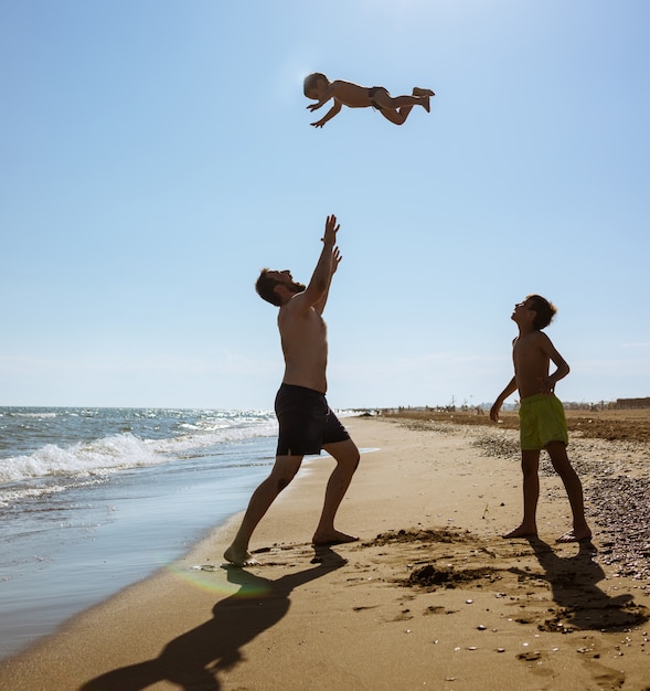 Ojciec i mężczyzna bawić się na piasek plaży miotaniu w lotniczym lataniu