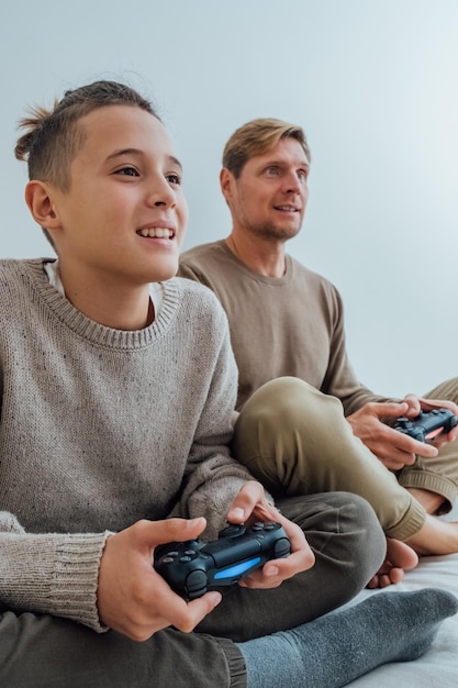 Ojciec i nastoletni syn z joystickami grają w gry wideo w domu