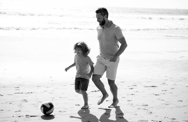 Ojciec i syn grają w piłkę nożną lub piłkę nożną na plaży tata z chłopcem w letni dzień