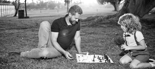 Ojciec i syn grają w szachy na trawie w letnich szachach parkowych