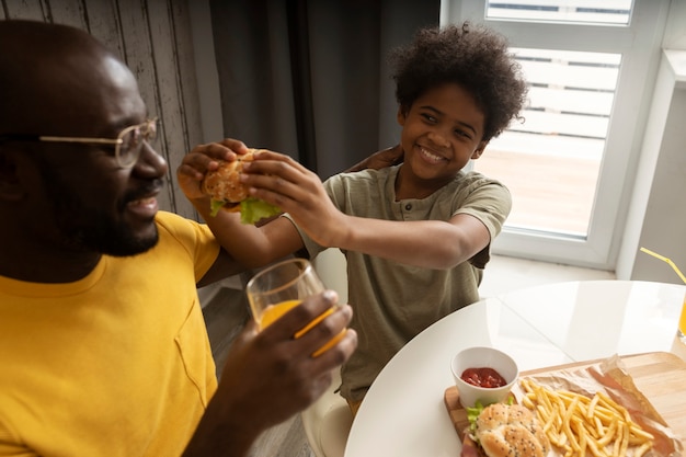 Ojciec i syn jedzą razem frytki i hamburgery
