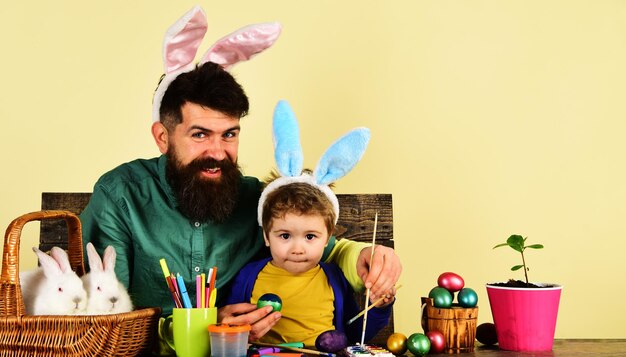 Ojciec i syn malują wielkanocne jajka, króliki, rodzinę, w, wielkanocny dzień, uśmiechnięty tata i uroczy dzieciak w