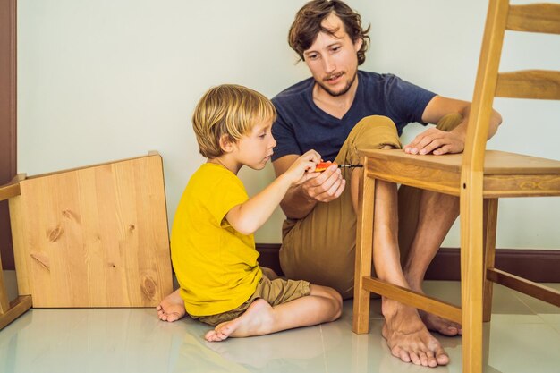 Ojciec i syn montują meble Chłopiec pomaga ojcu w domu Koncepcja Happy Family