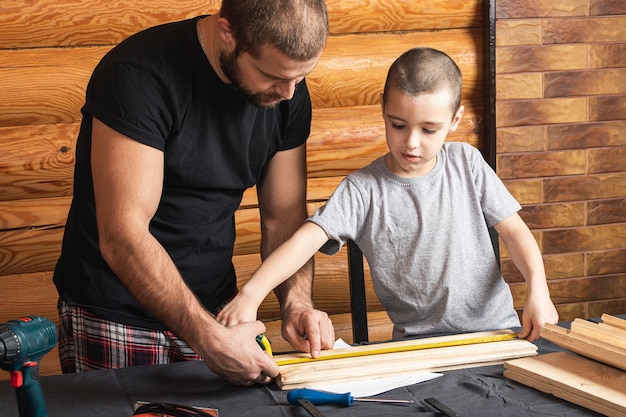 Zdjęcie ojciec i syn razem wykonują drewnianą ptaszarnię w warsztacie