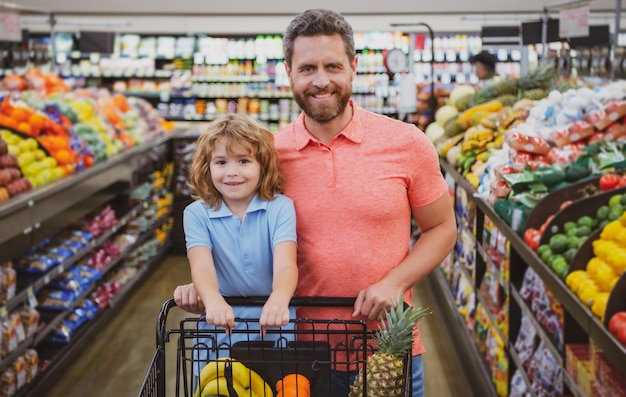 Ojciec i syn z koszykiem kupujący jedzenie w sklepie spożywczym Rodzina klientów kupujący produkty w supermarkecie